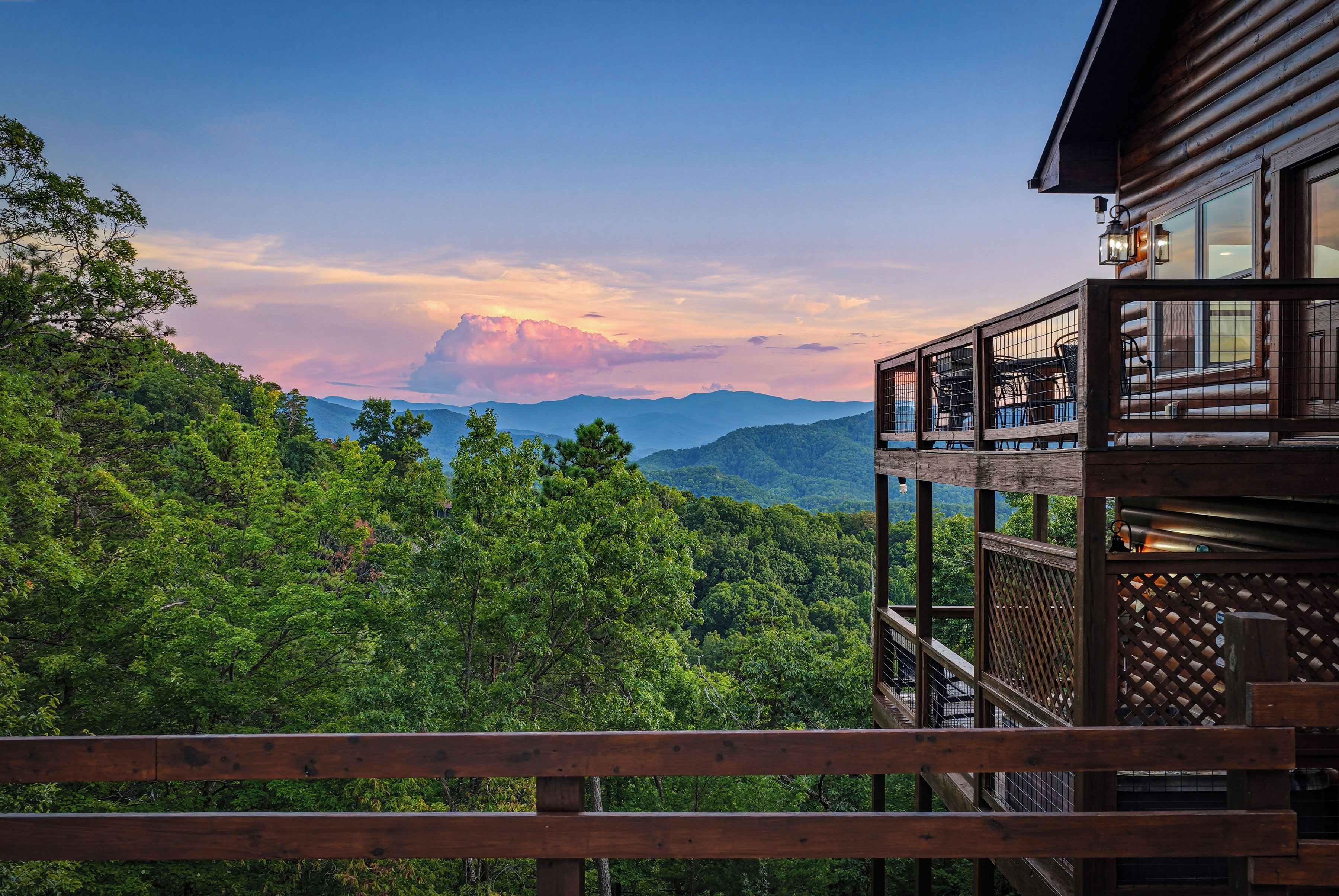 A wooden balcony with a view of a forested mountain range.
