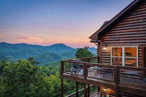 A wooden cabin with a deck and a table, overlooking a mountainous landscape. - New Listing, Game Room, Hot Tub, Free Attractions, Mountain View (Sevierville)