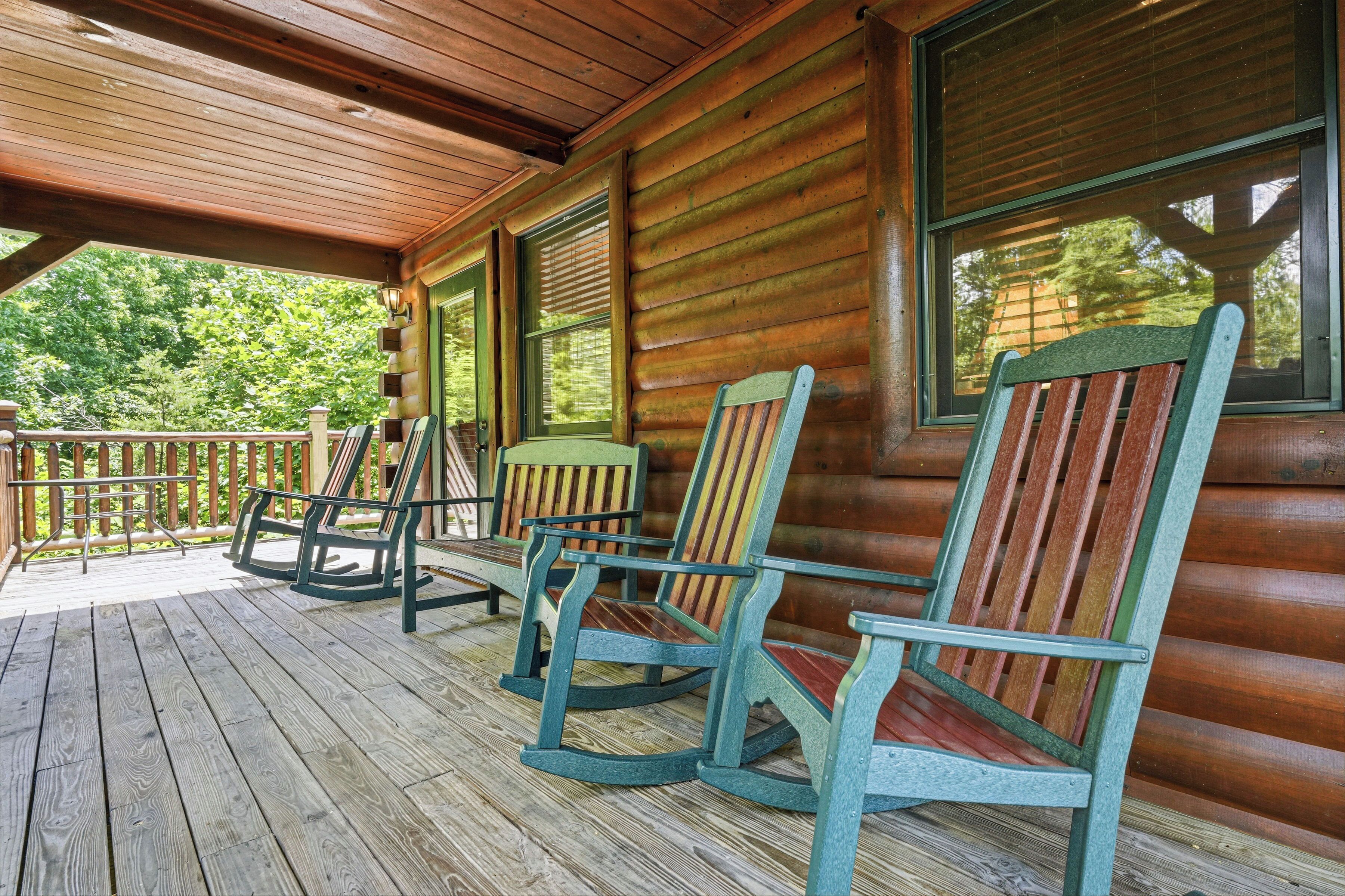 Eine hölzerne Veranda mit Schaukelstühlen und einem Tisch, mit Blick auf ein bewaldetes Gebiet.