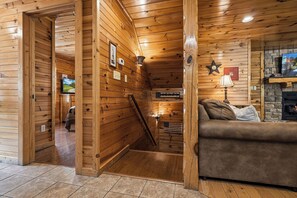 Ein Holzblockhaus-Interieur mit Kamin, einer Couch und einem Fernseher.