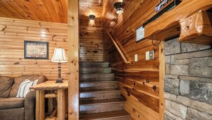 Un interno in legno con una scala, un divano, una lampada e un quadro incorniciato.