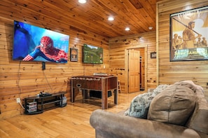 A wooden-paneled room with a TV, a foosball table, and a couch. - New Listing | 5BR Gatlinburg Cabin w/ Hot Tub + Game Room + Free Tickets (Gatlinburg)
