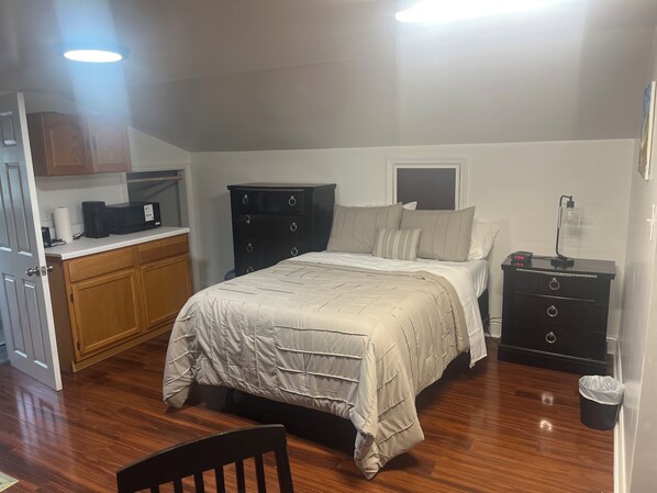A bedroom with a bed, dresser, and a desk with a computer.