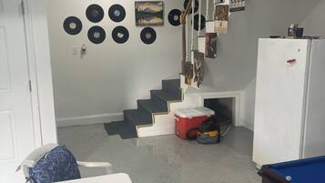 A room with a pool table, a staircase, and a wall decorated with vinyl records.