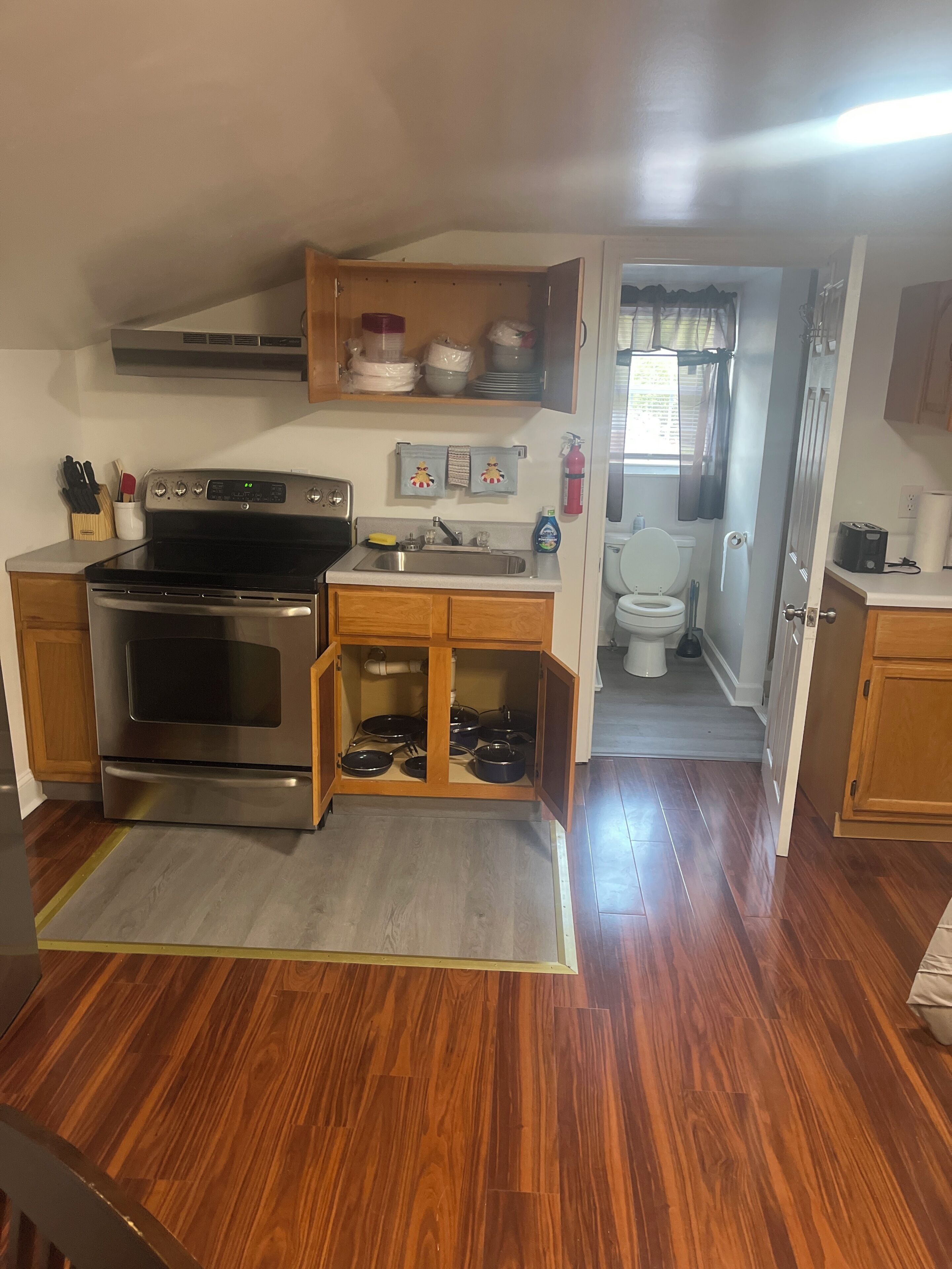 A compact kitchen with a built-in oven, a sink, and wooden cabinets.