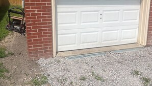 A garage with a white door, a brick wall, and a sign indicating the address '385 SHOP'.