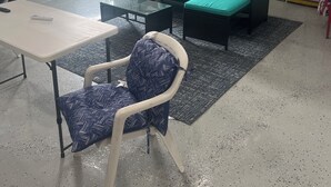 A garage with a green sofa, a white table, and a patterned chair.