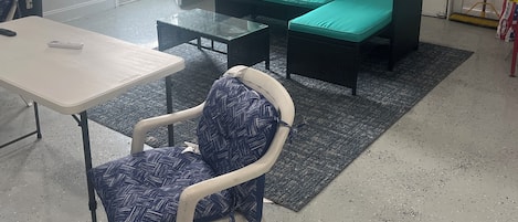 A garage with a green sofa, a white table, and a patterned chair.
