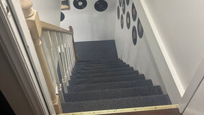 A staircase with a wooden handrail, carpeted steps, and a wall decorated with vinyl records.