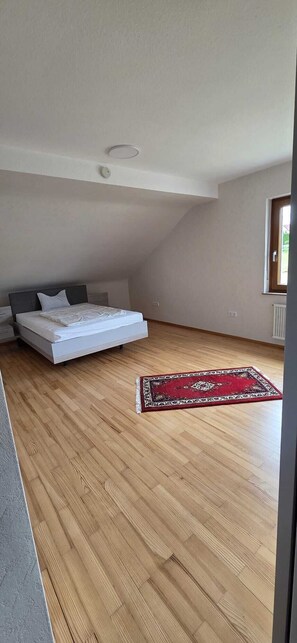 A bedroom with a bed, a red patterned rug, and a sloped ceiling.