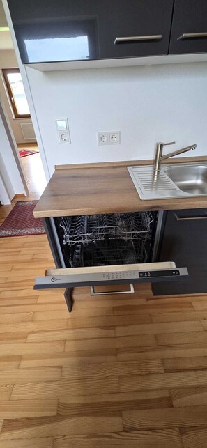 A kitchen with a dishwasher, a sink, and a wooden countertop.