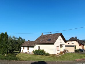 A two-story house with a sloped roof, a small window, and a chimney.