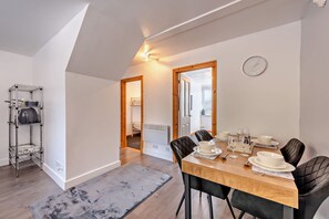 A dining area with a wooden table, black chairs, and a clock on the wall. - Host Stay The Coach House (Worthing)