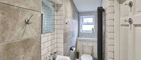 A bathroom with a white sink, a toilet, and a mirror. There is a window above the toilet.