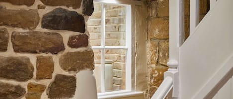 A stone wall with a window and a white staircase.