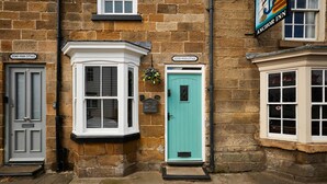 A row of cottages with distinct front doors and windows, each with a unique nameplate. - Host Stay - Hidden Winds Cottage (Guisborough)