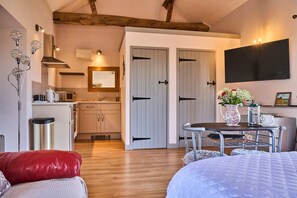 A cozy bedroom with a bed, a small table with a vase of flowers, and a red pillow. - Host Stay Snowy Owl Barn (Thetford)