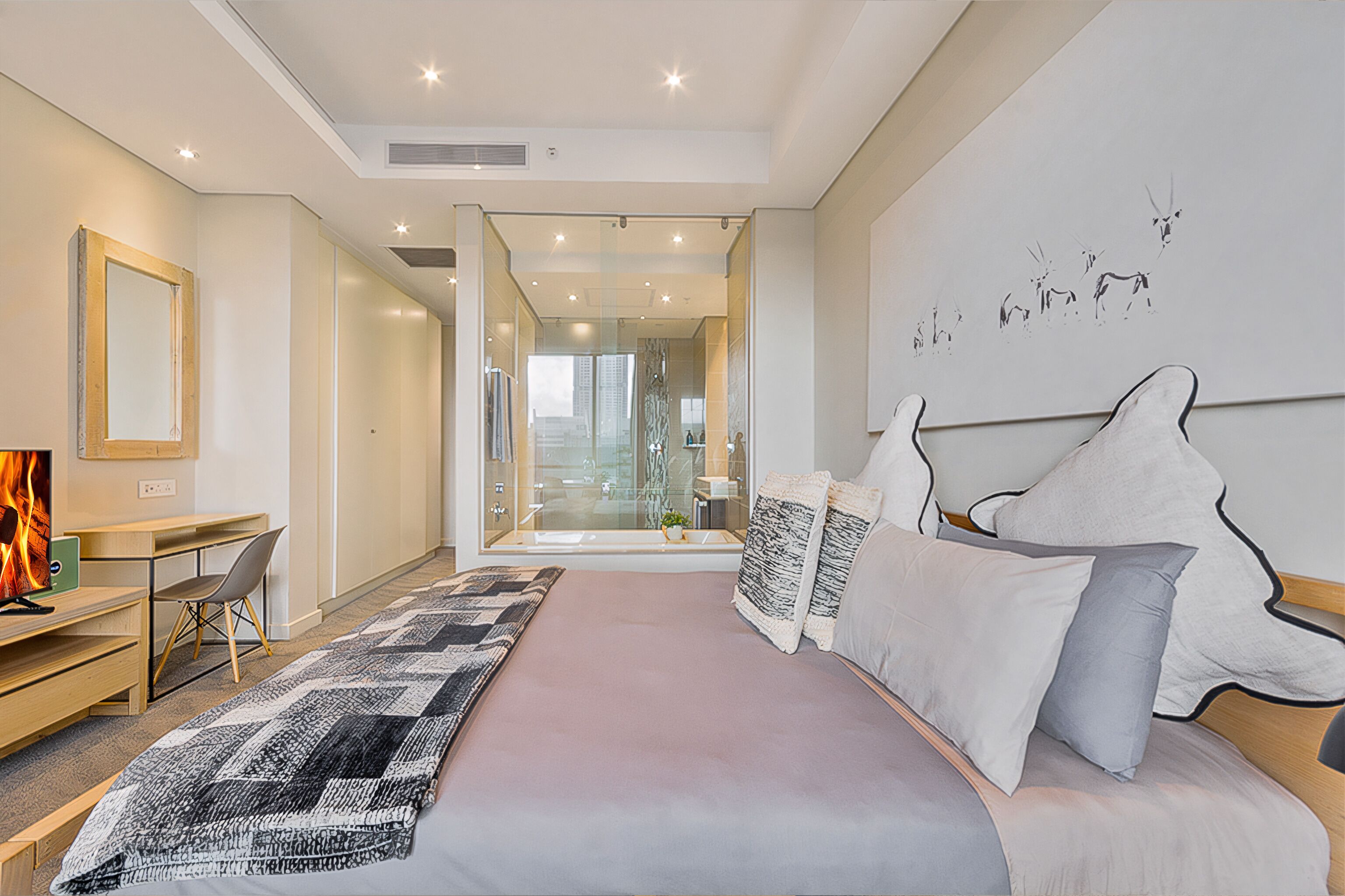 Habitación de hotel moderna con una cama grande, un escritorio y vistas de la ciudad a través de un ventanal.
