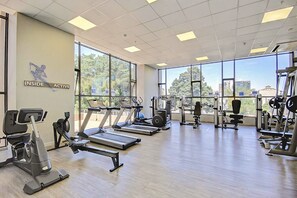 Un gimnasio con cintas de correr, elípticas y equipo de pesas.