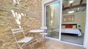 A room with a stone wall, a sliding glass door leading to a bed, and a small table with chairs. - 1BR near Malvarrosa beach Cabanyal R53 (Valencia / València)