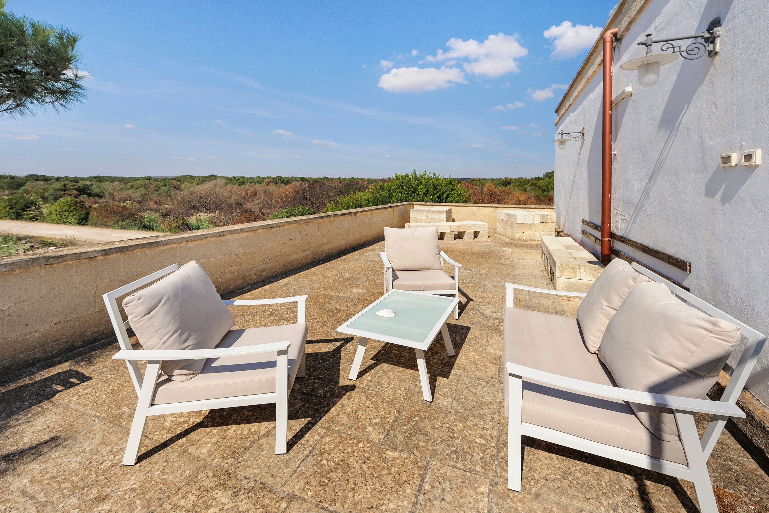 Eine Terrass mit Gartenmöbeln, einem Tisch und Blick auf die Landschaft.