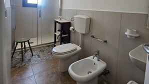 Een badkamer met toilet, bidet, wastafel en een klein krukje.