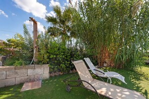 A garden with a lawn, a wooden structure, and a white lounge chair.