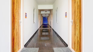 A hallway with wooden doors, a blue carpeted area, and a tiled floor. - Collection O Sarjapura Road Kasavanahall (Bengaluru)