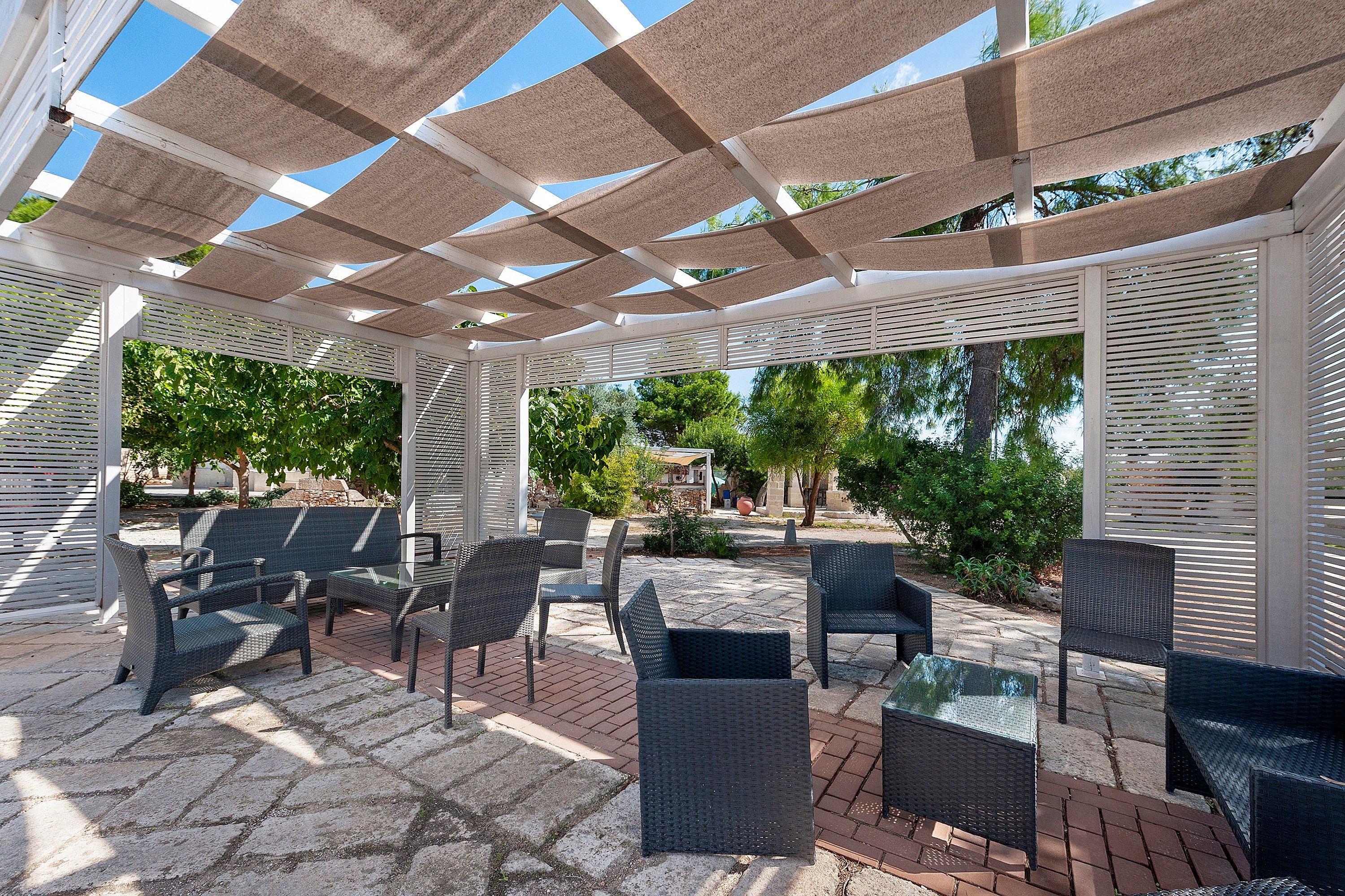 Ein überdachter Außenbereich mit Korbmöbeln und einer Pergola.