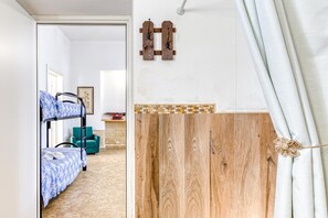 Quarto com beliches, porta de madeira e cortina com detalhe de corda.