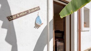 Une entrée d’immeuble avec une enseigne en bois, un objet décoratif bleu et une plante en pot.