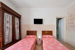 Ein Zimmer mit zwei Holzbetten, einem Wand-Fernseher und einer Ziegelwand.