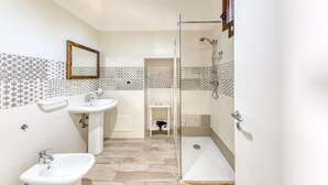 Une salle de bain avec deux lavabos, un miroir et un espace douche.