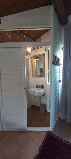 A bathroom with a white sink, a mirror, and a chandelier. - 'Giardino Antico' with Shared Garden and Wi-Fi (Montecarotto)
