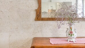 Een structuurwand met een houten spiegel en een vaas met bloemen op een houten tafel.