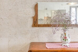 Una parete strutturata con uno specchio in legno e un vaso con fiori su un tavolo di legno.
