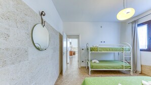 Een kamer met stapelbedden, een spiegel en een hanglamp.