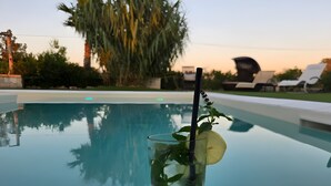 A glass of drink with a straw and a lemon slice on a poolside table. - Melograno Room (Porto Cesareo)
