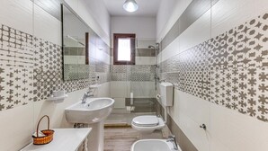 A bathroom with two sinks, a toilet, and a shower. There is a mirror above the sinks and a window above the shower. - Melograno Room (Porto Cesareo)