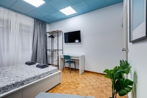 A bedroom with a bed, a desk, a chair, a TV, and a plant. - BFR - Aurelio&Vatican Rooms (Rome)