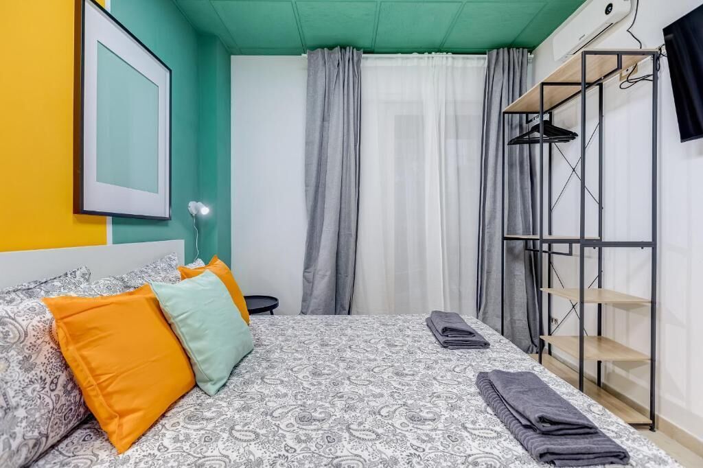 A bedroom with a bed, pillows, a wardrobe, and a window with curtains.