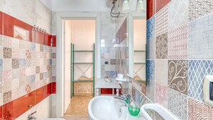 A bathroom with a sink, bidet, and shower area, featuring a variety of patterned tiles. - Corbezzolo Room – Ground Floor, 4 Beds, Air Conditioning, Private Bath (Porto Cesareo)