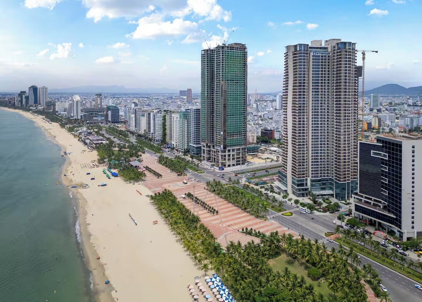 Panorama costiero con grattacieli, una spiaggia e una strada con veicoli.