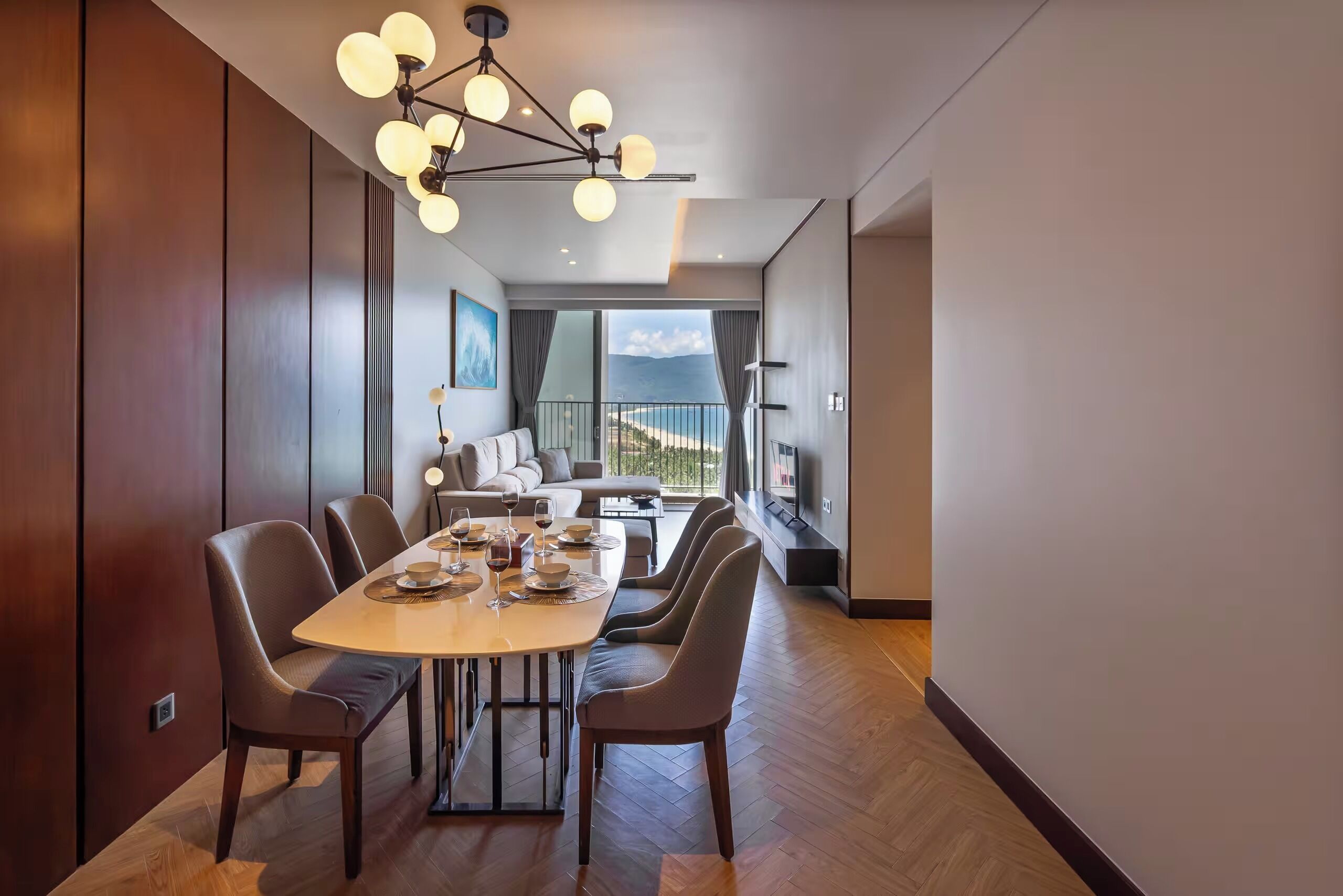 A modern dining area with a large table, multiple chairs, and a contemporary chandelier.
