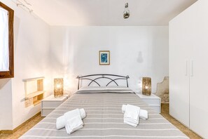 Ein Schlafzimmer mit einem Bett, zwei Nachttischen, einem Kleiderschrank und einer Wandlampe.