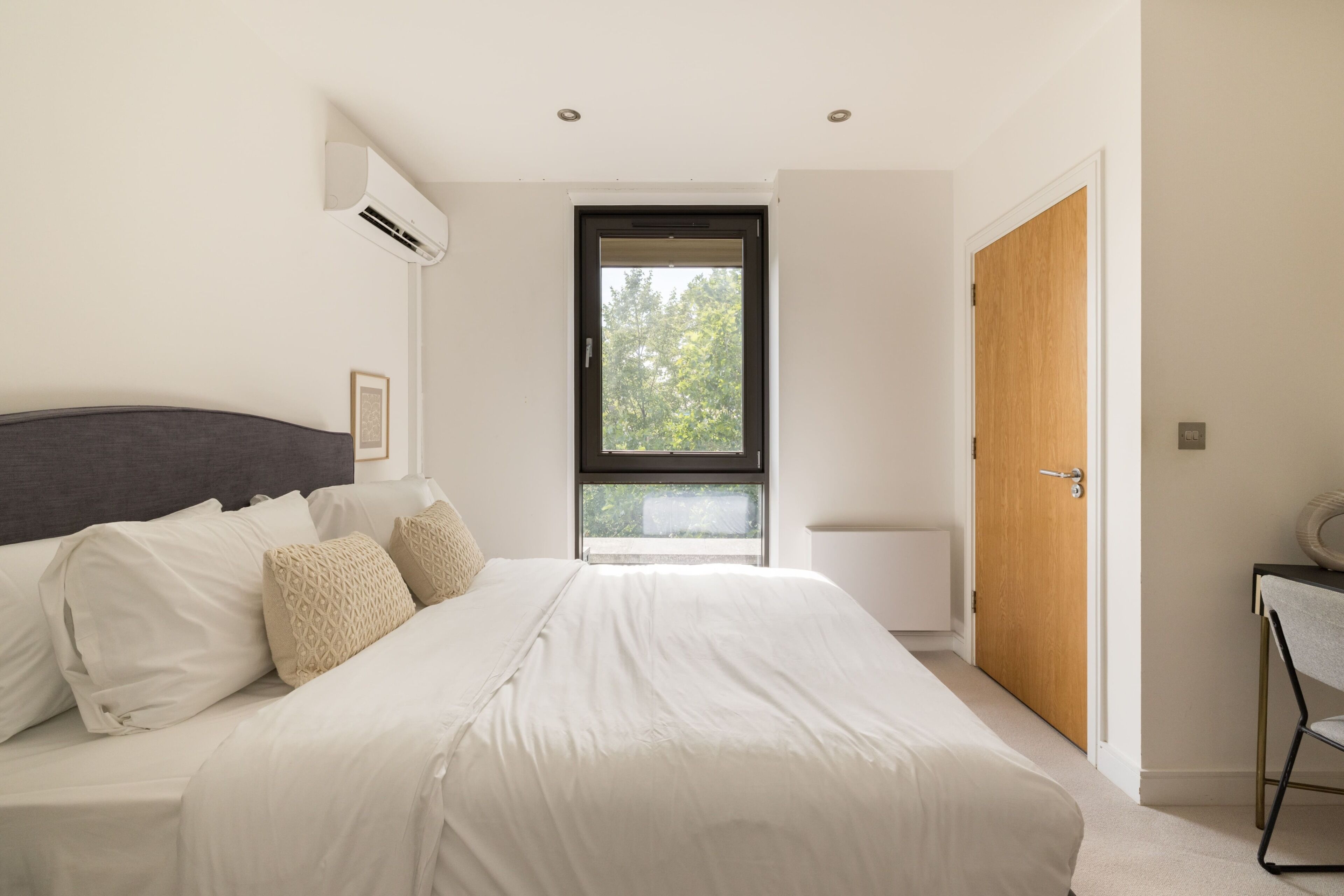 Ein Schlafzimmer mit einem Bett, einem Fenster, einer Tür und einer Klimaanlage.