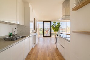 A modern kitchen with a view of the city through large windows. - Terrace Light in the Vale (London)