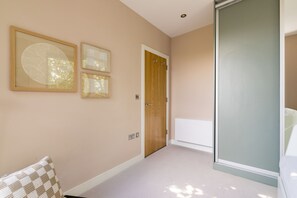 A hallway with a door, a radiator, and framed artwork on the wall. - Terrace Light in the Vale (London)