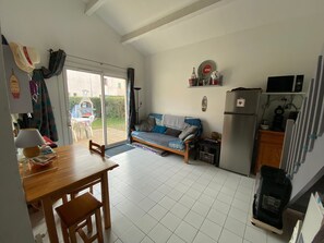 A compact living space with a dining area, a sofa, a refrigerator, and a microwave. - Detached holiday home with terrace, private garden, and air conditioning (Saint-Cyprien)