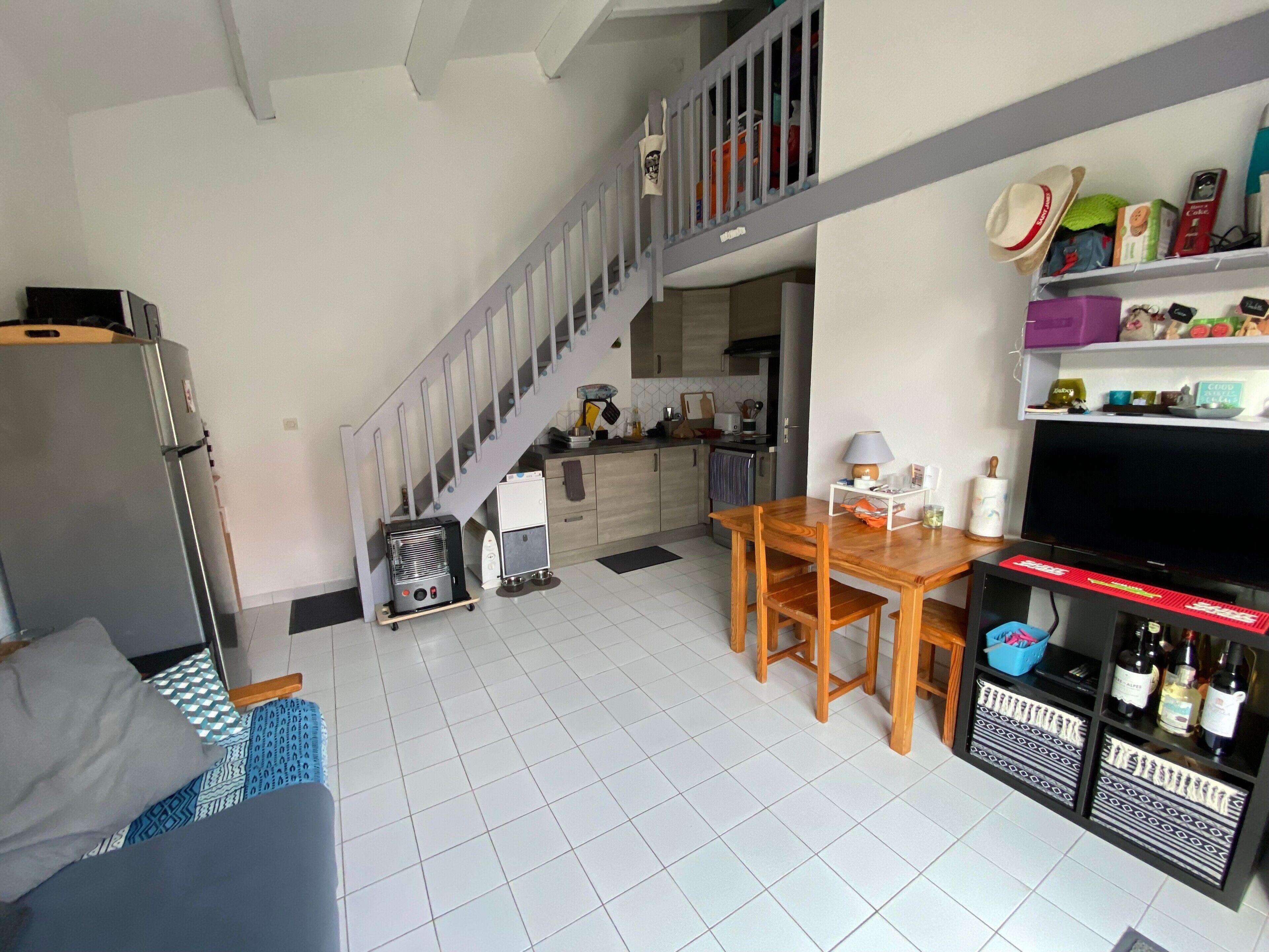 A compact living space with a kitchen, dining area, and a staircase leading to an upper level.